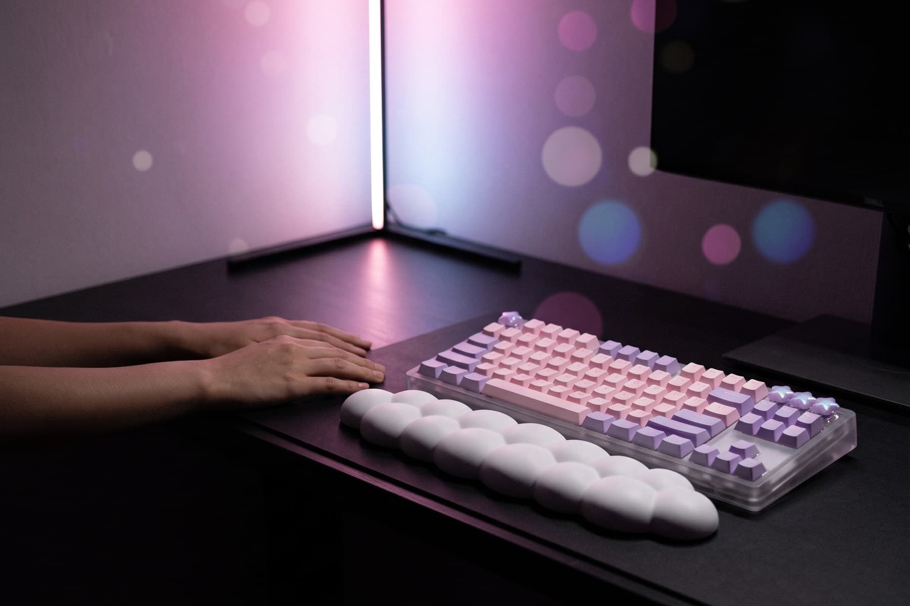 Desk at night lit only by an L-Shaped Corner RGB floor lamp in soft purple, with lavender star keycaps and a Dreamy Cloud Bubble wrist rest